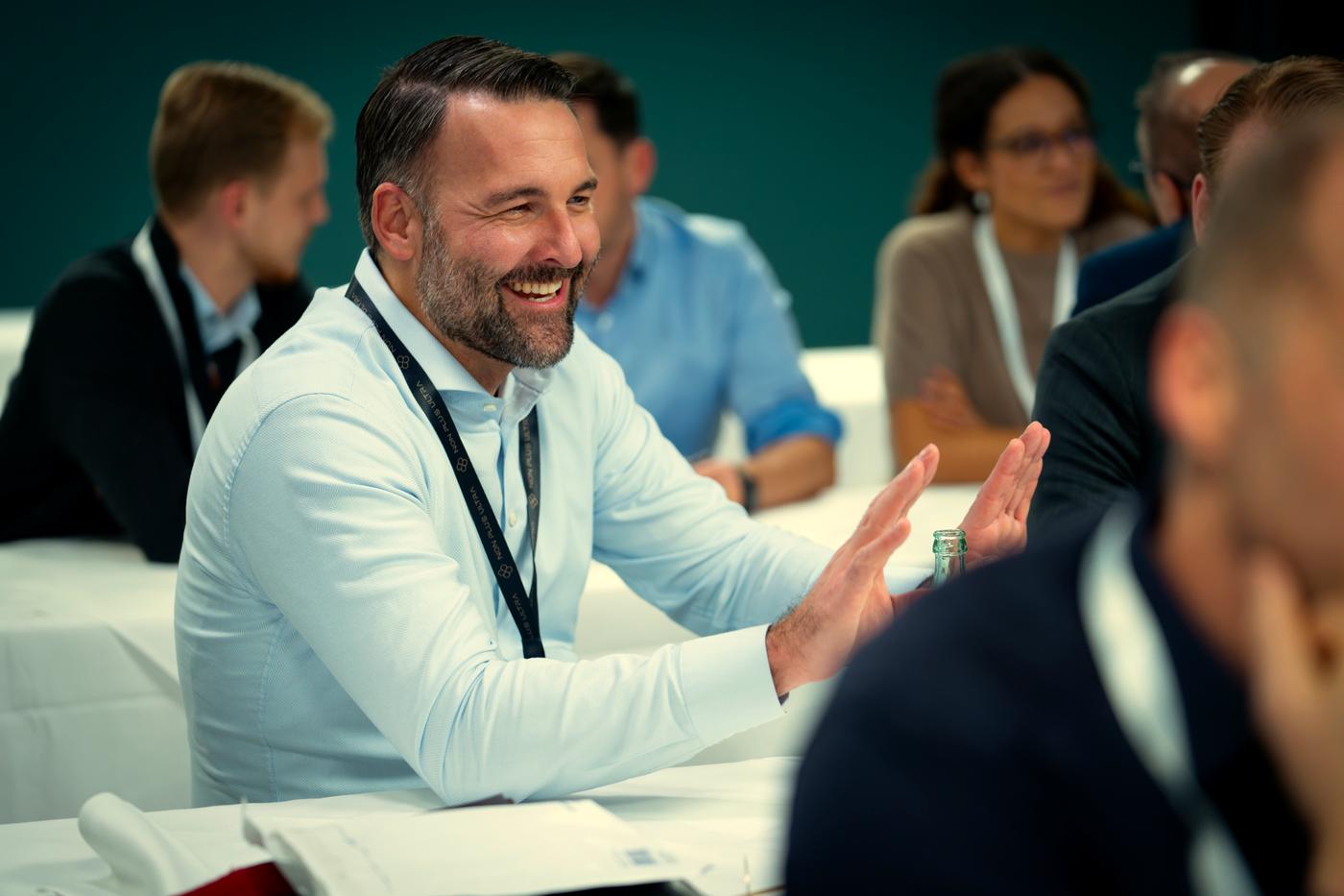 Lachender Unternehmer im Gespräch beim Networking am Geschäftsführertag